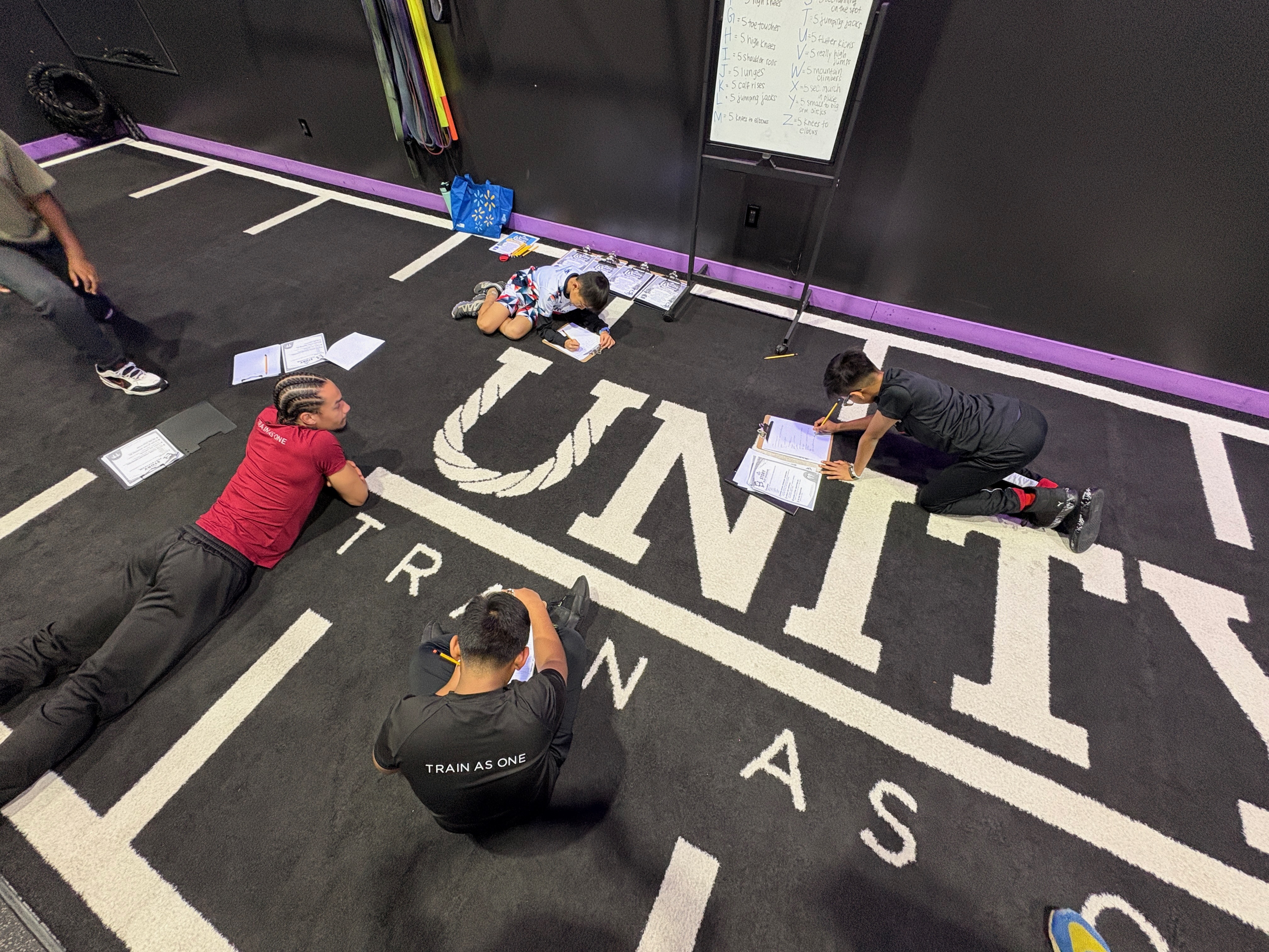 Kids and UNITY coaches on the gym floor, all writing stories together